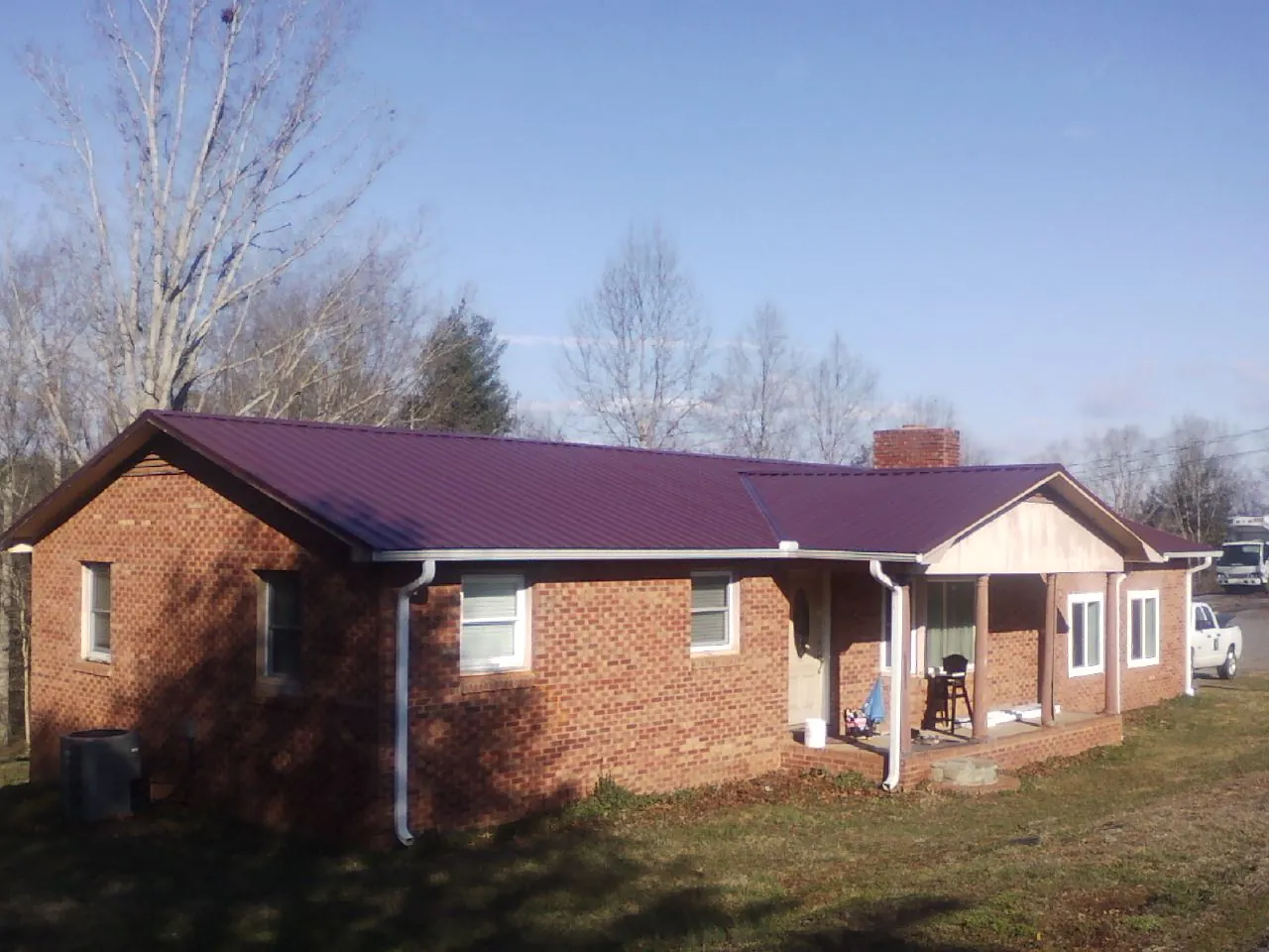 Burgundy metal roof on a brick ranch home with a new addition in Canon City