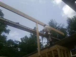 Carpenter setting a ridge beam over a new addition frame — Ice Dam Removal by Roofing Brothers in Canon City