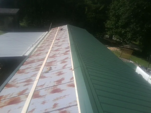Old rusted panels beside newly installed green metal roofing — Wind Damage Roof Repair by Roofing Brothers in Canon City