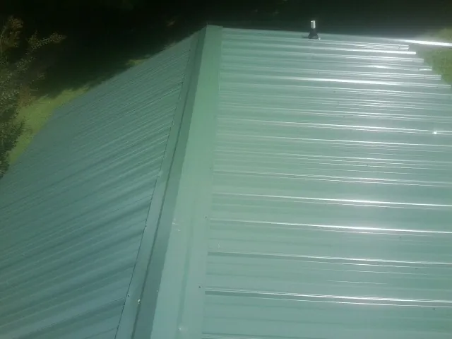 New green metal panels meeting at the ridge of a roof — Flat Roof Repair work by our crew in Canon City
