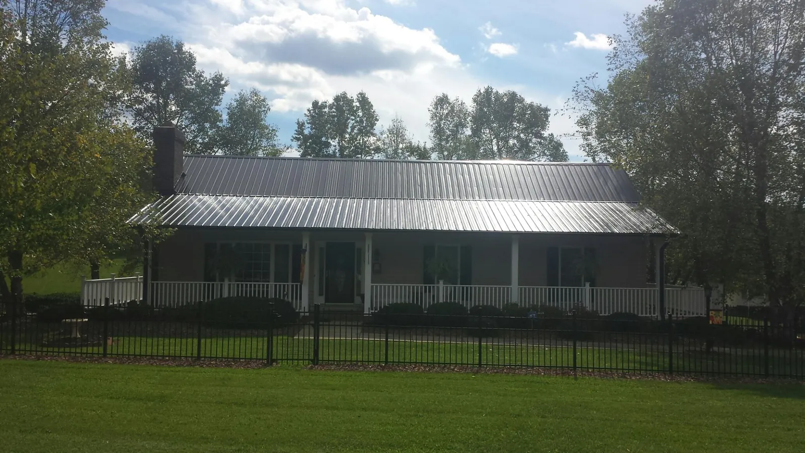 Gray metal roof on a brick ranch with a full width front porch — Gutter Guard Installation work by our crew in Canon City