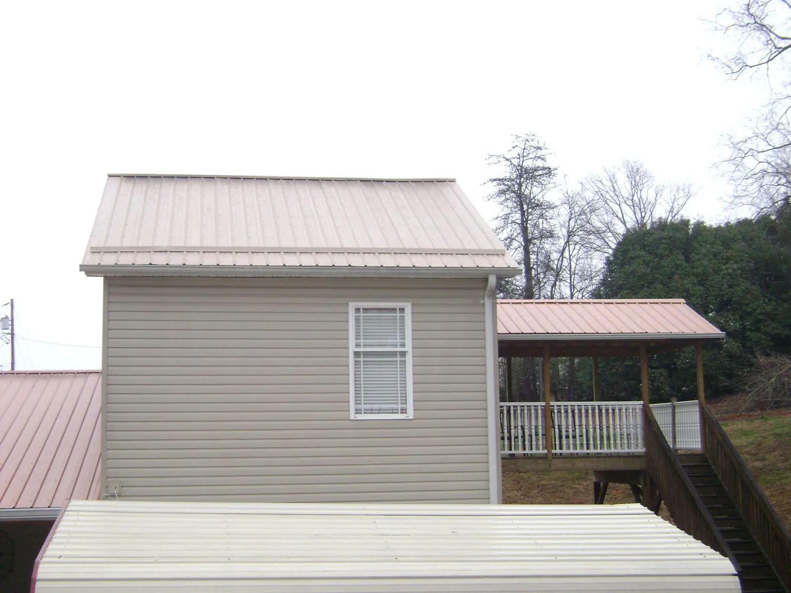 Tan metal roofs on a two story addition and attached porch, from a Roof Replacement job in Canon City