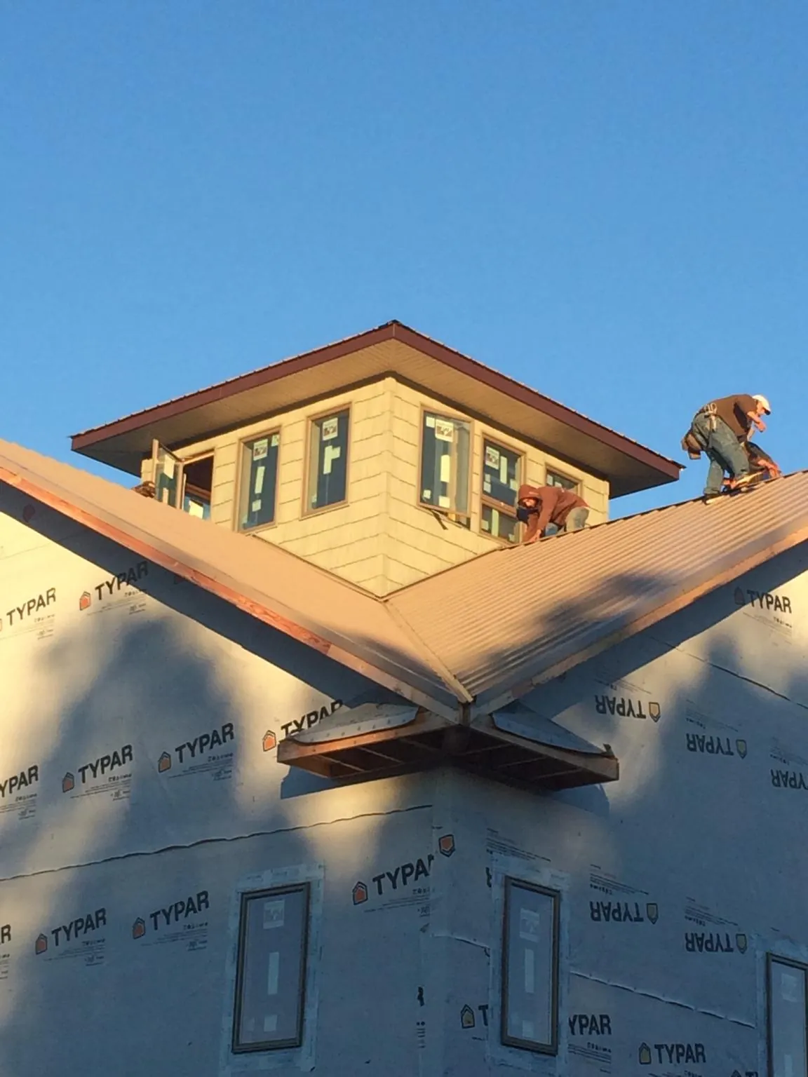 Roofers working around a rooftop cupola on a new metal roof at sunset — Roof Waterproofing in Canon City by Roofing Brothers